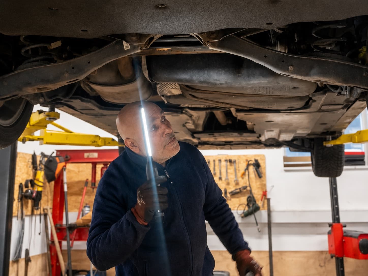 Mekaniker arbejder under en bil ved koblingsskift hos Super Auto i Hillerød